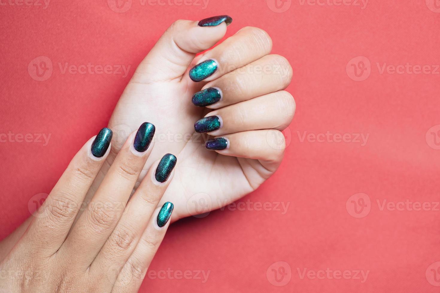 Primer plano de las manos de una hermosa mujer arreglada con diseño de uñas verde primavera verano sobre fondo rojo. concepto de salón de belleza de manicura y pedicura. copie el espacio para el texto. uñas largas con pantano - esmalte en gel. foto