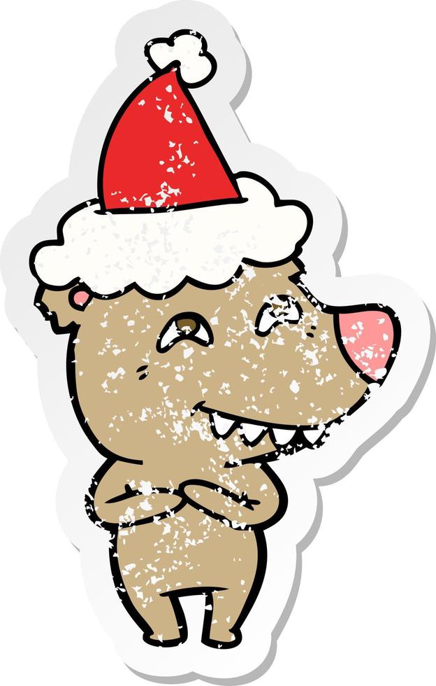 distressed sticker cartoon of a bear showing teeth wearing santa hat vector