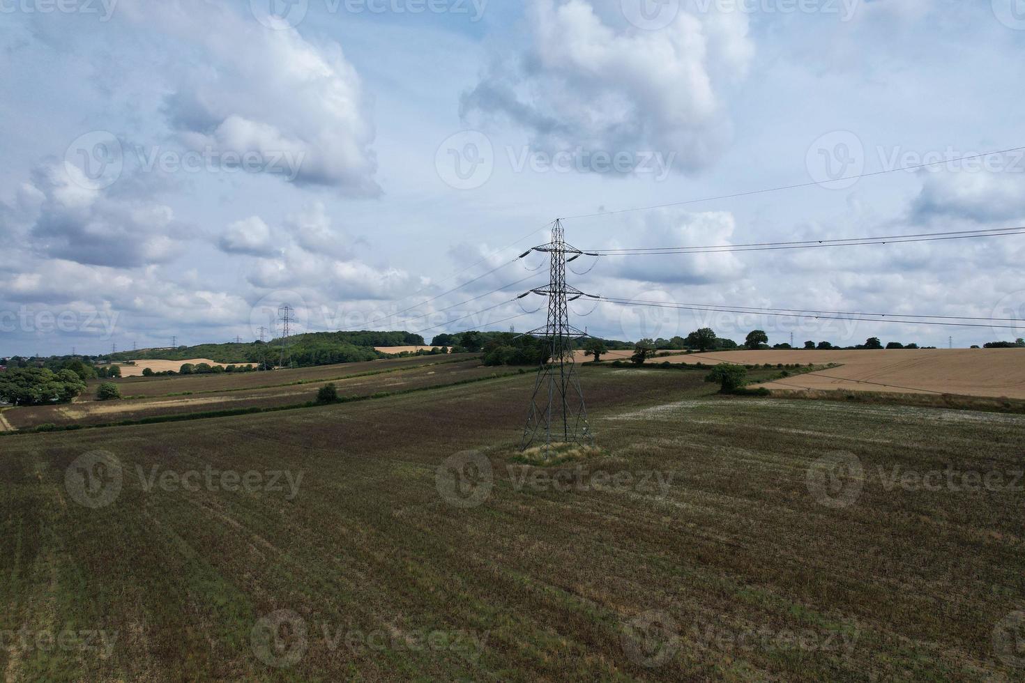 High Voltage Power Supply Poles with Cables Running Through British Farmlands and Countryside, Aerial high angle view by drone's camera. photo