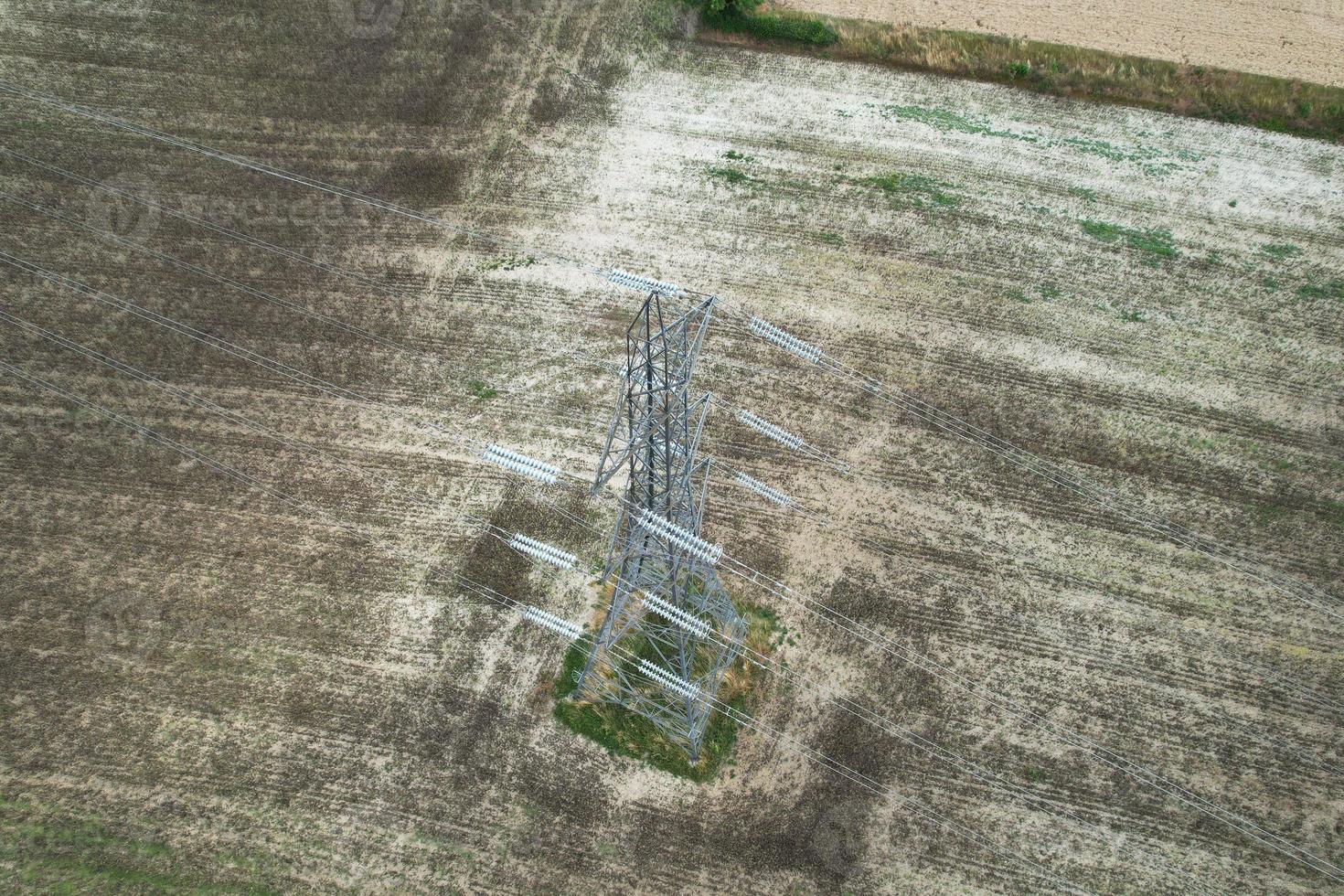 High Voltage Power Supply Poles with Cables Running Through British Farmlands and Countryside, Aerial high angle view by drone's camera. photo