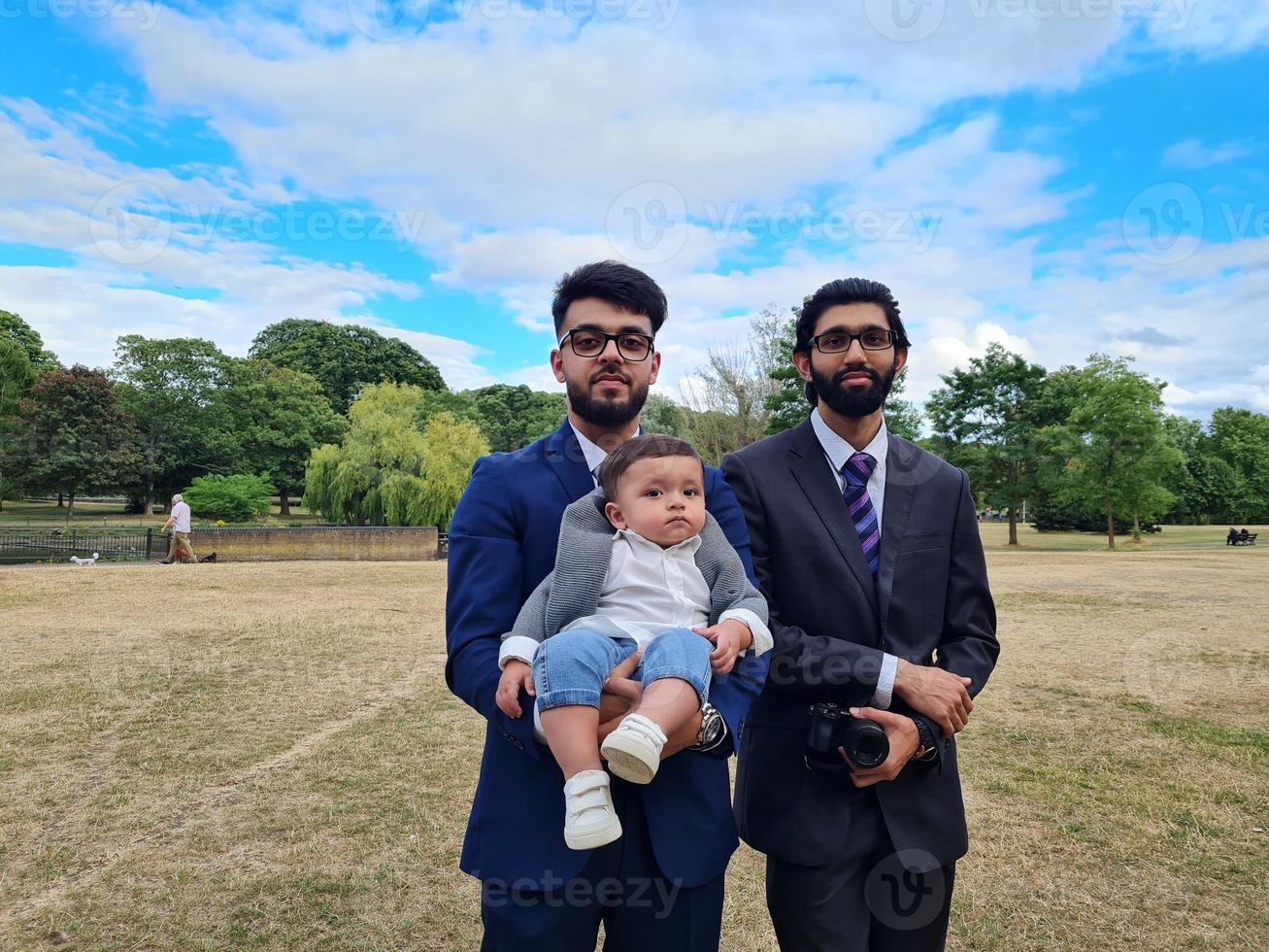 2 Young Asian Males are Walking with an Infant Baby Boy at Local Public Park of Luton England UK photo