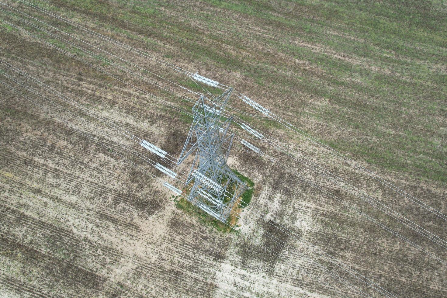 High Voltage Power Supply Poles with Cables Running Through British Farmlands and Countryside, Aerial high angle view by drone's camera. photo