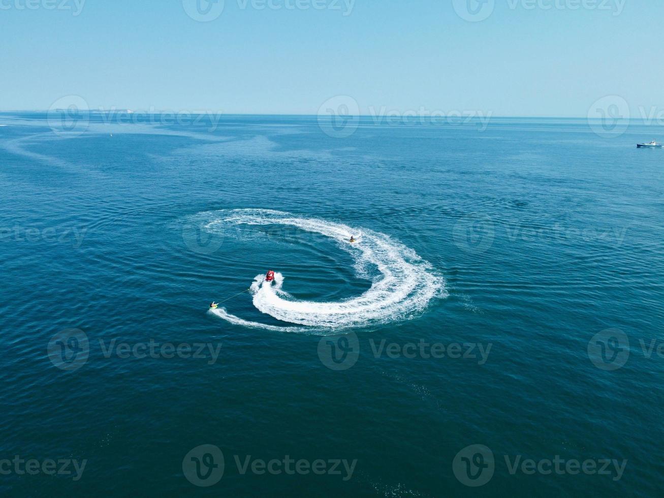 High Angle Footage and Aerial view of Ocean with High Speed Boats, People are having fun and enjoying hottest weather at Bournemouth Beach Sea Front of England UK. photo