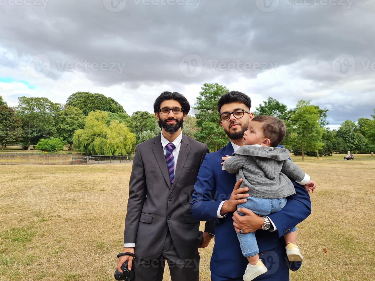 2 Young Asian Males are Walking with an Infant Baby Boy at Local Public Park of Luton England UK photo