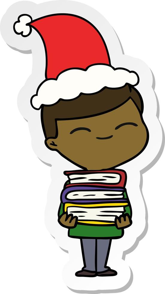 sticker cartoon of a smiling boy with stack of books wearing santa hat vector