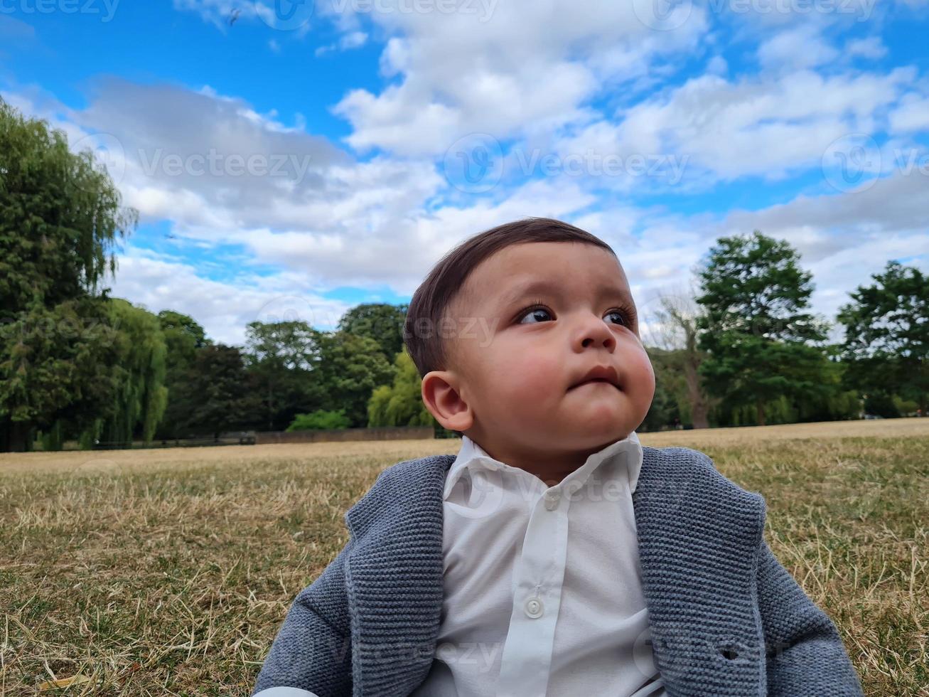 lindo bebé pequeño está posando en un parque público local de la ciudad de luton de inglaterra reino unido foto