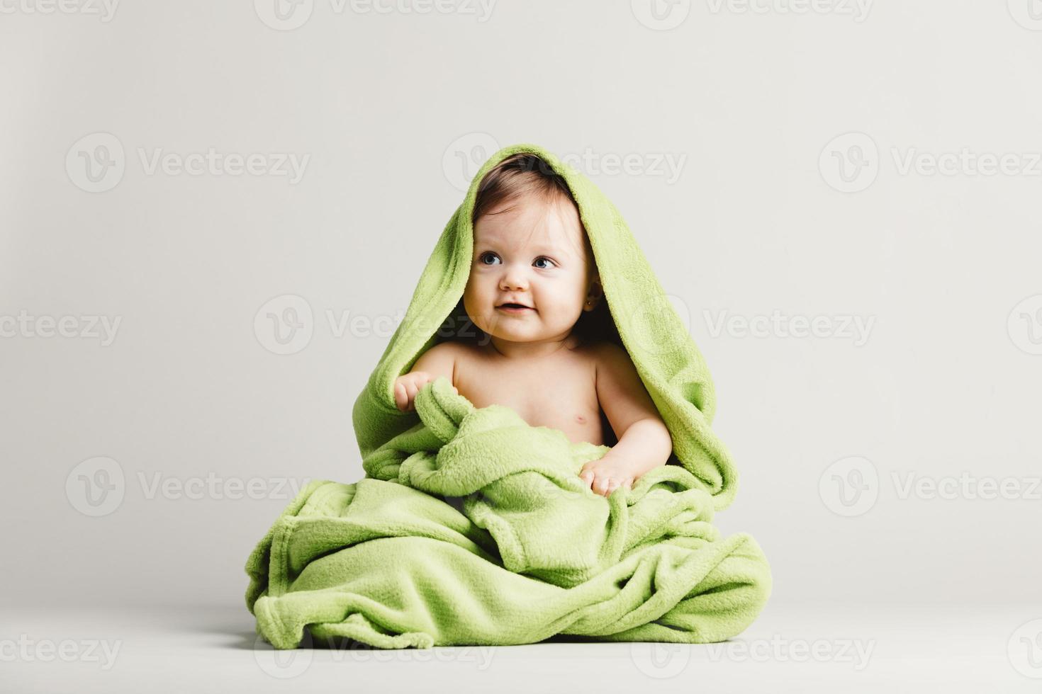 Cute baby girl covered in green blanket. photo