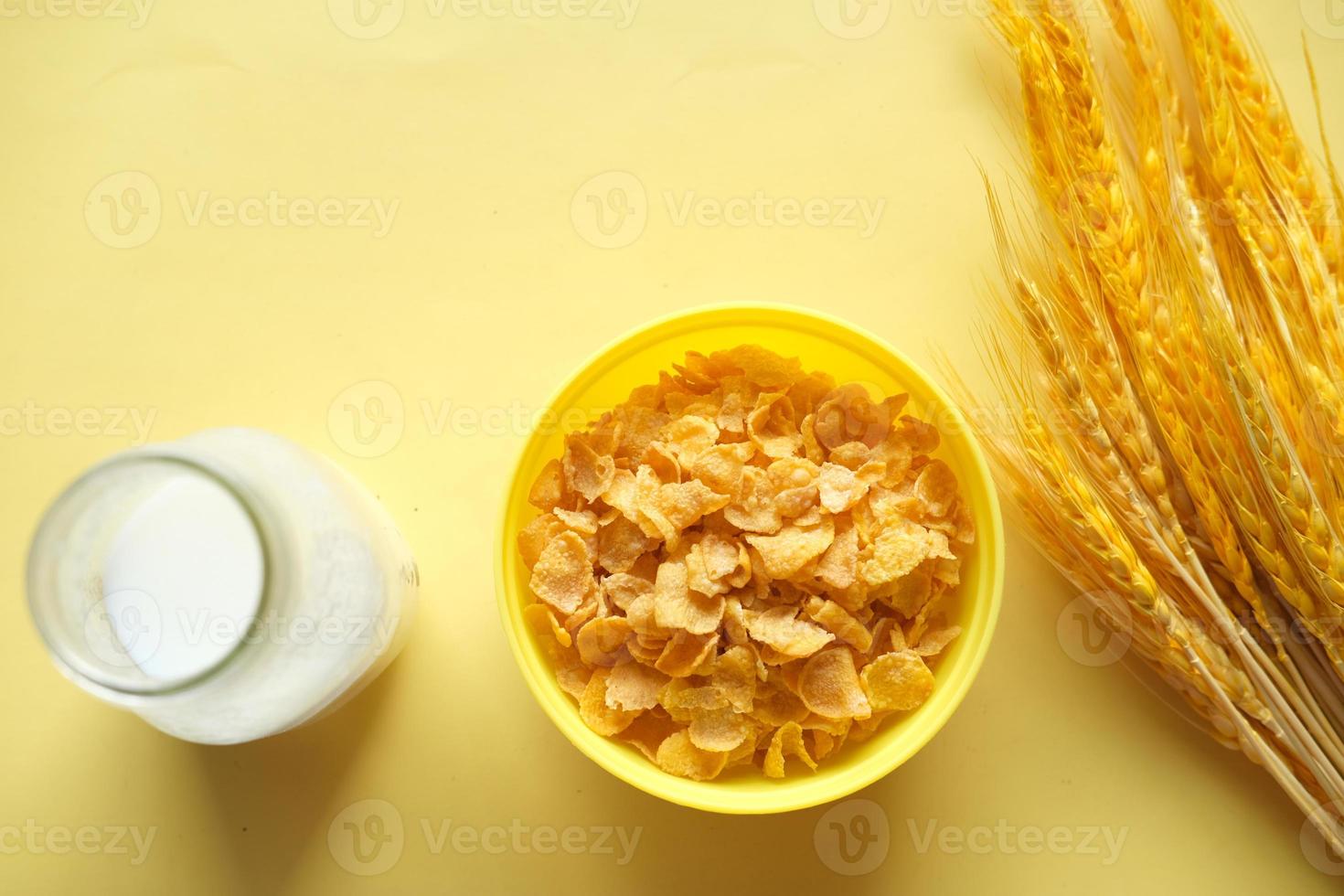 milk jar and corn flakes on yellow background photo