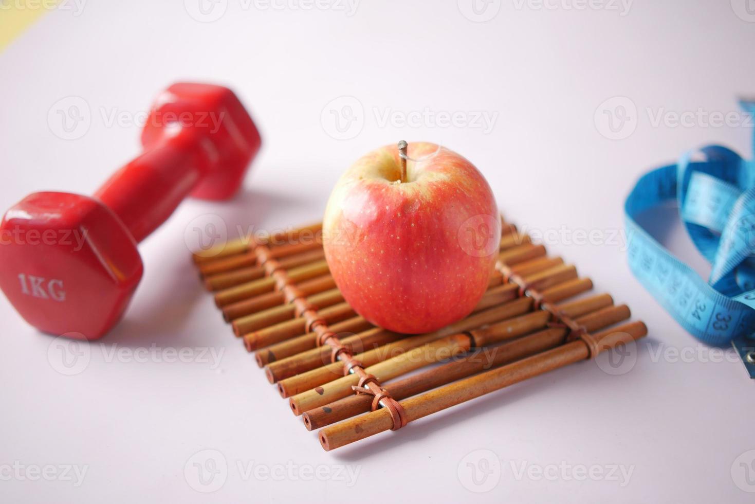 fresh drinking water, apple and a pink color dumbbell on table photo