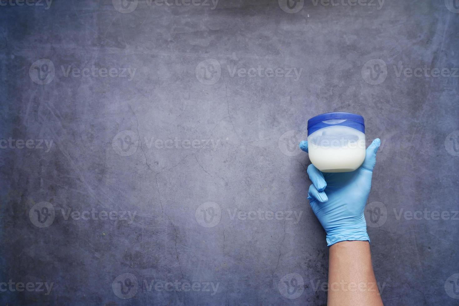 top view of hand in latex gloves holding a petroleum jelly container photo