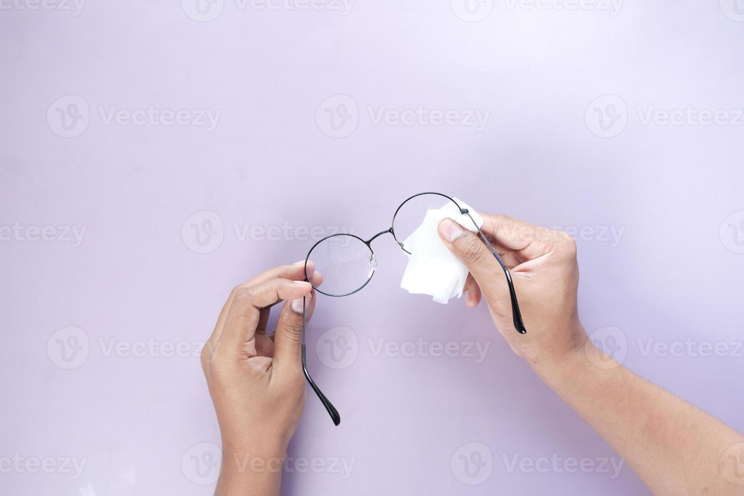 cleaning eyeglass with tissue close up photo