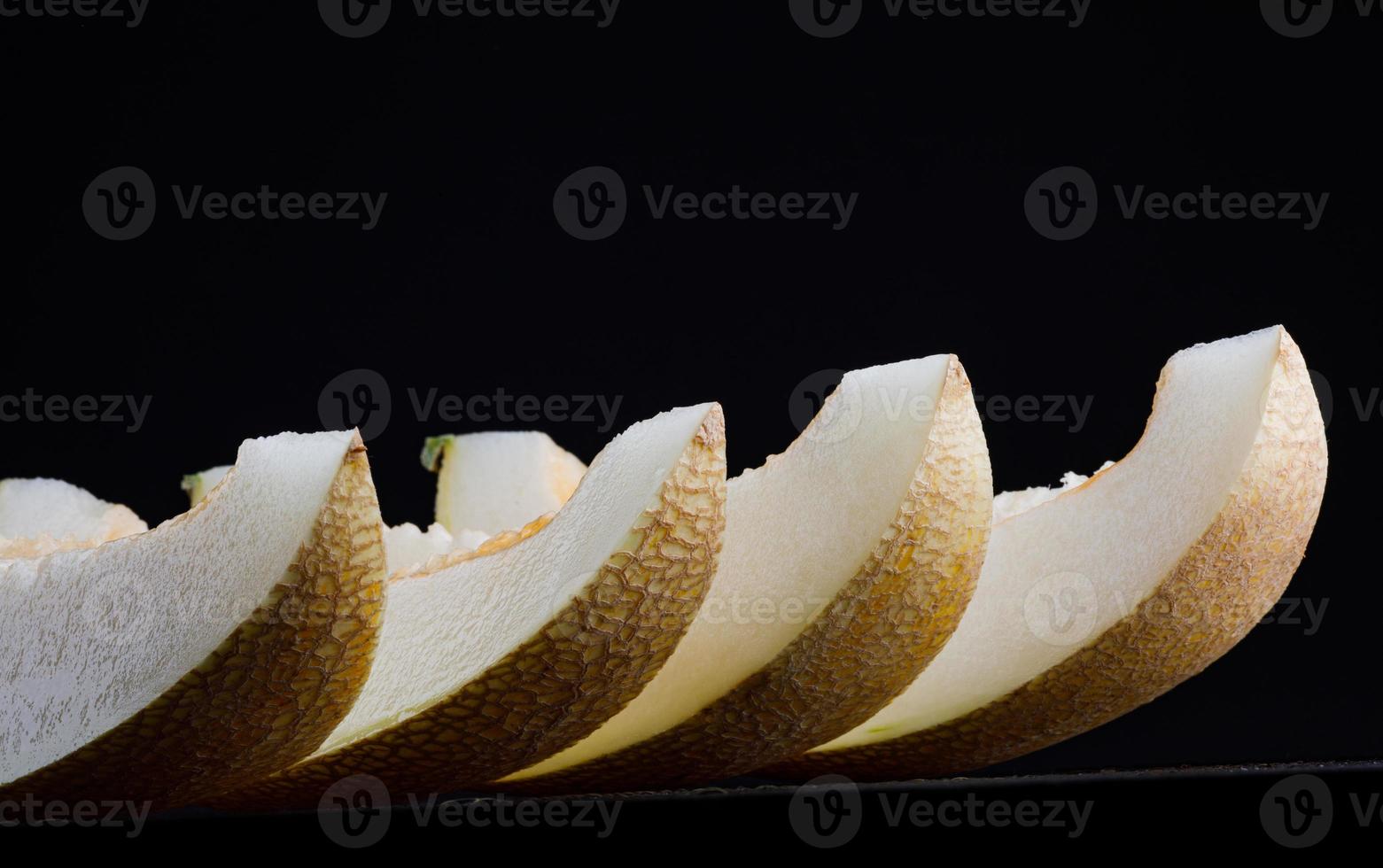 A row of lobes of ripe juicy melon on a black background.. photo
