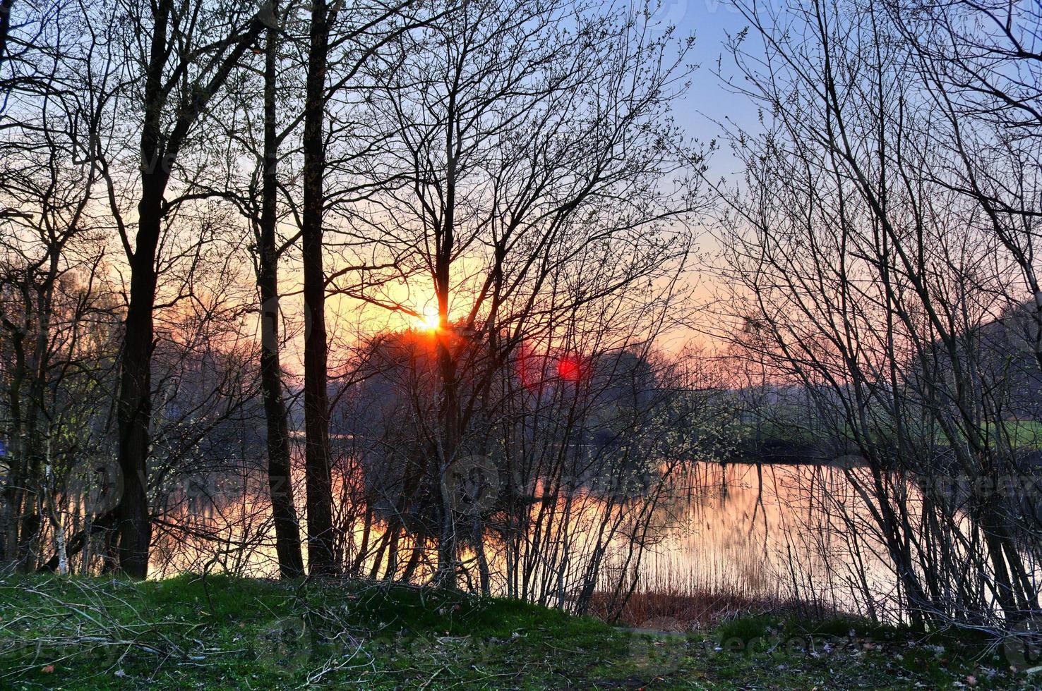 bella y romántica puesta de sol en un lago de colores amarillo y naranja foto