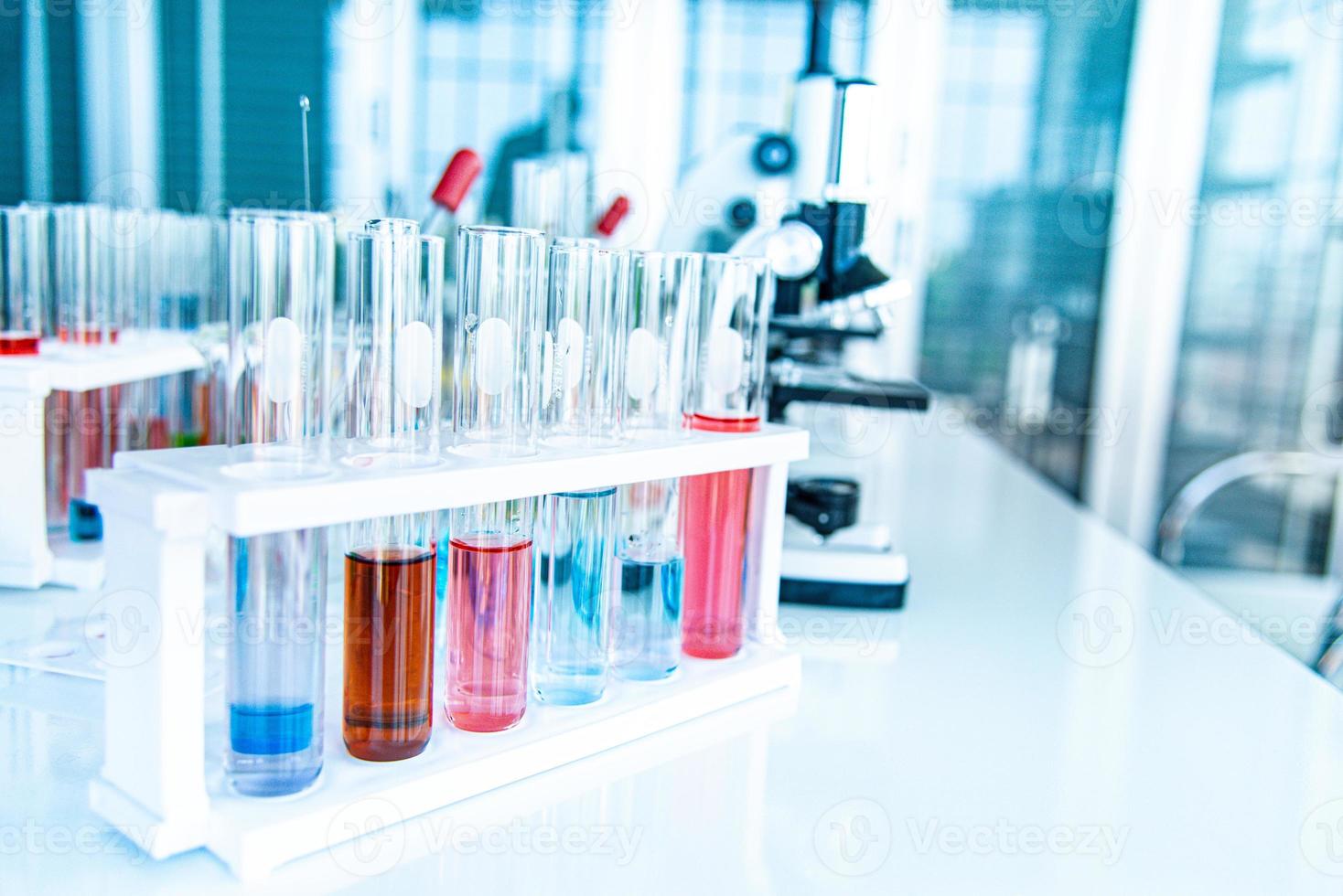 preparación de equipos de laboratorio como cristalería, tubo con azul y líquido sobre la mesa blanca. el experimento químico en la investigación científica foto