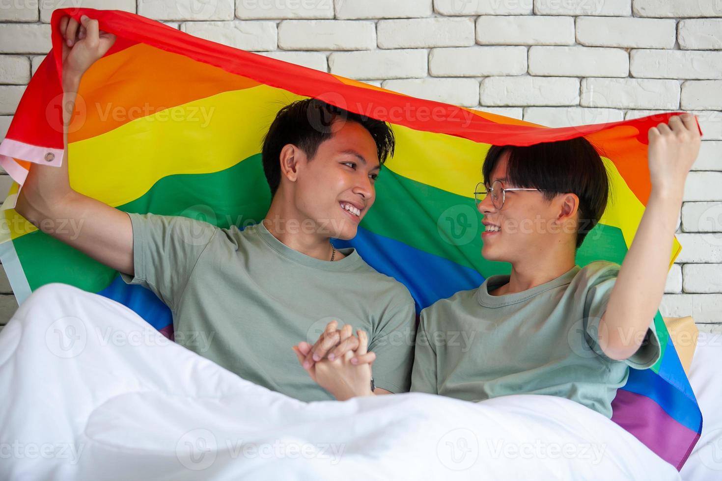 Happy asian gay couple holding hands together relaxing at home on bed, LGBTQ concept. photo