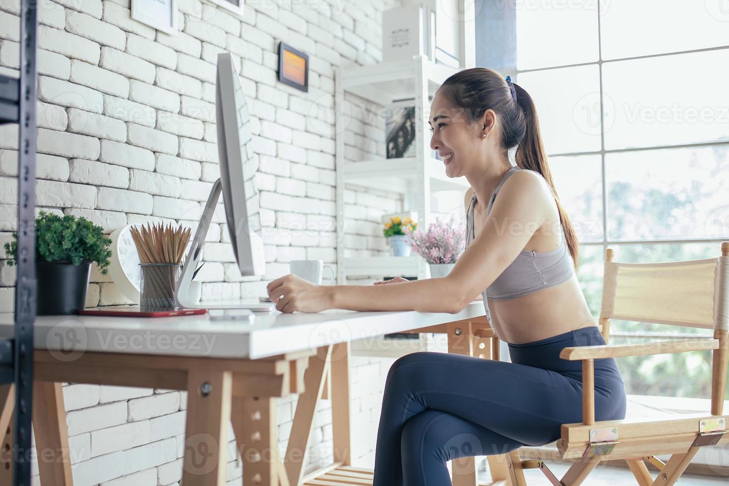 Young Asian woman using laptop computer checking social media application on website online at home, feel relax and enjoy communicate and discuss  in living room. photo