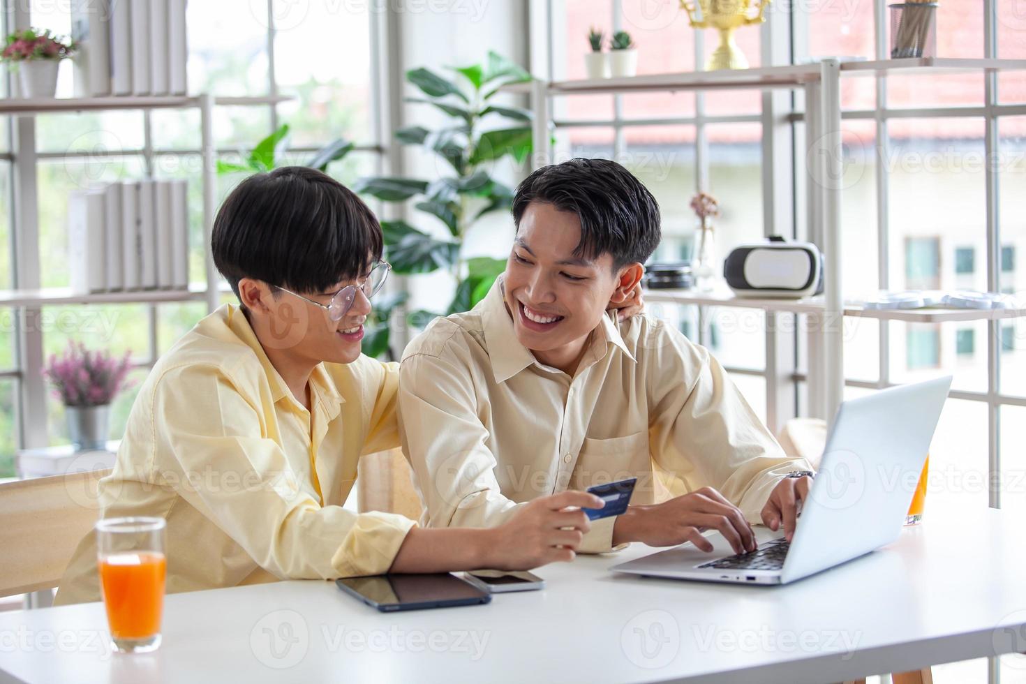 Asian gay couples are using laptop or shopping online with credit card,  LGBTQ concept. photo