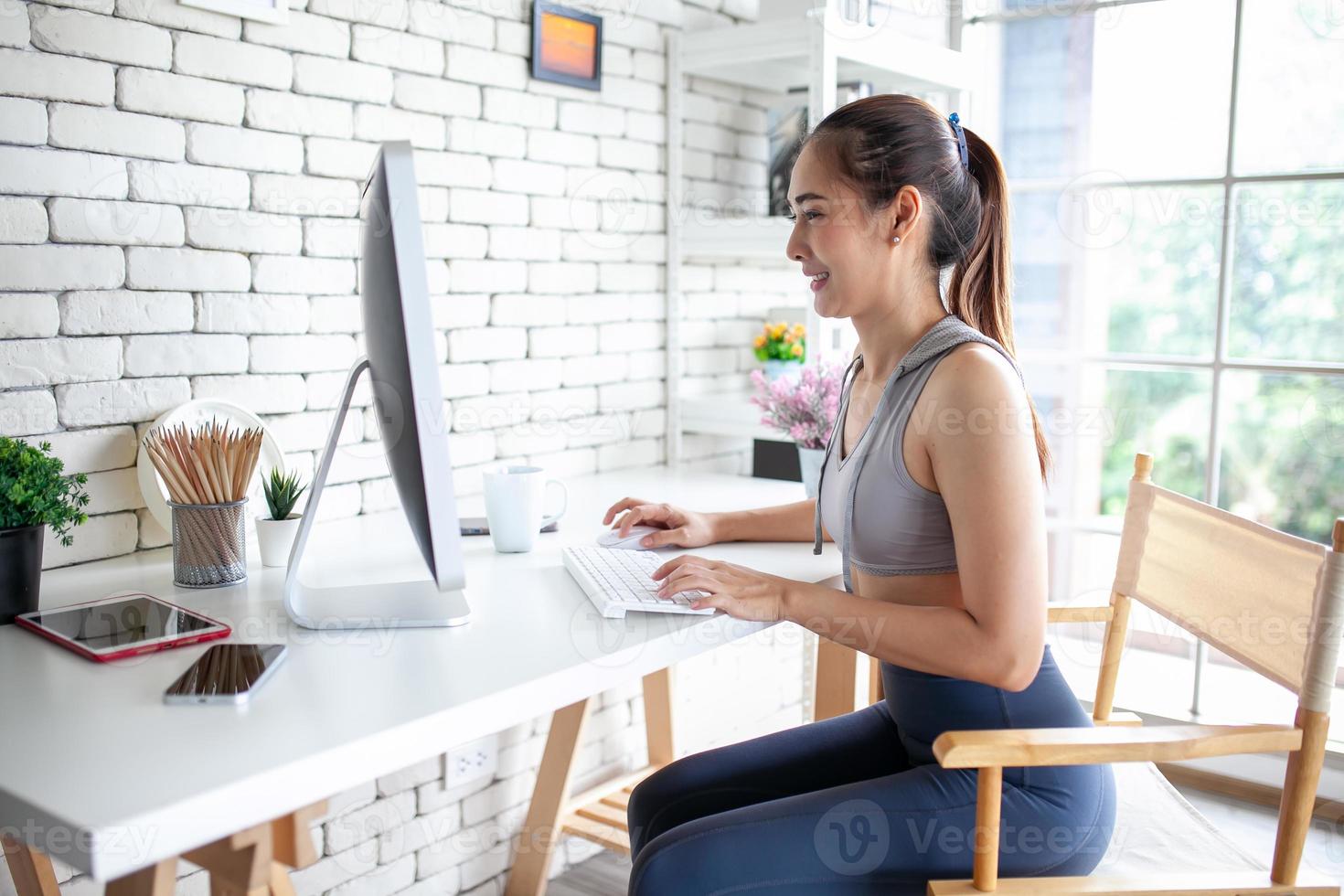 Young Asian woman using laptop computer checking social media application on website online at home, feel relax and enjoy communicate and discuss  in living room. photo