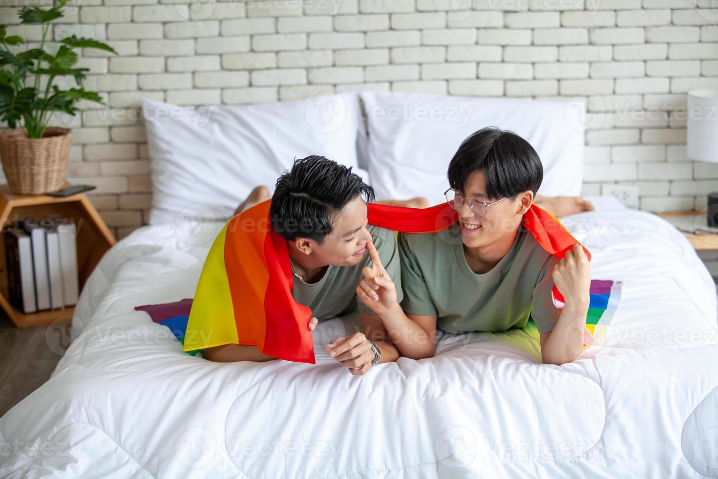 Happy asian gay couple holding hands together relaxing at home on bed, LGBTQ concept. photo