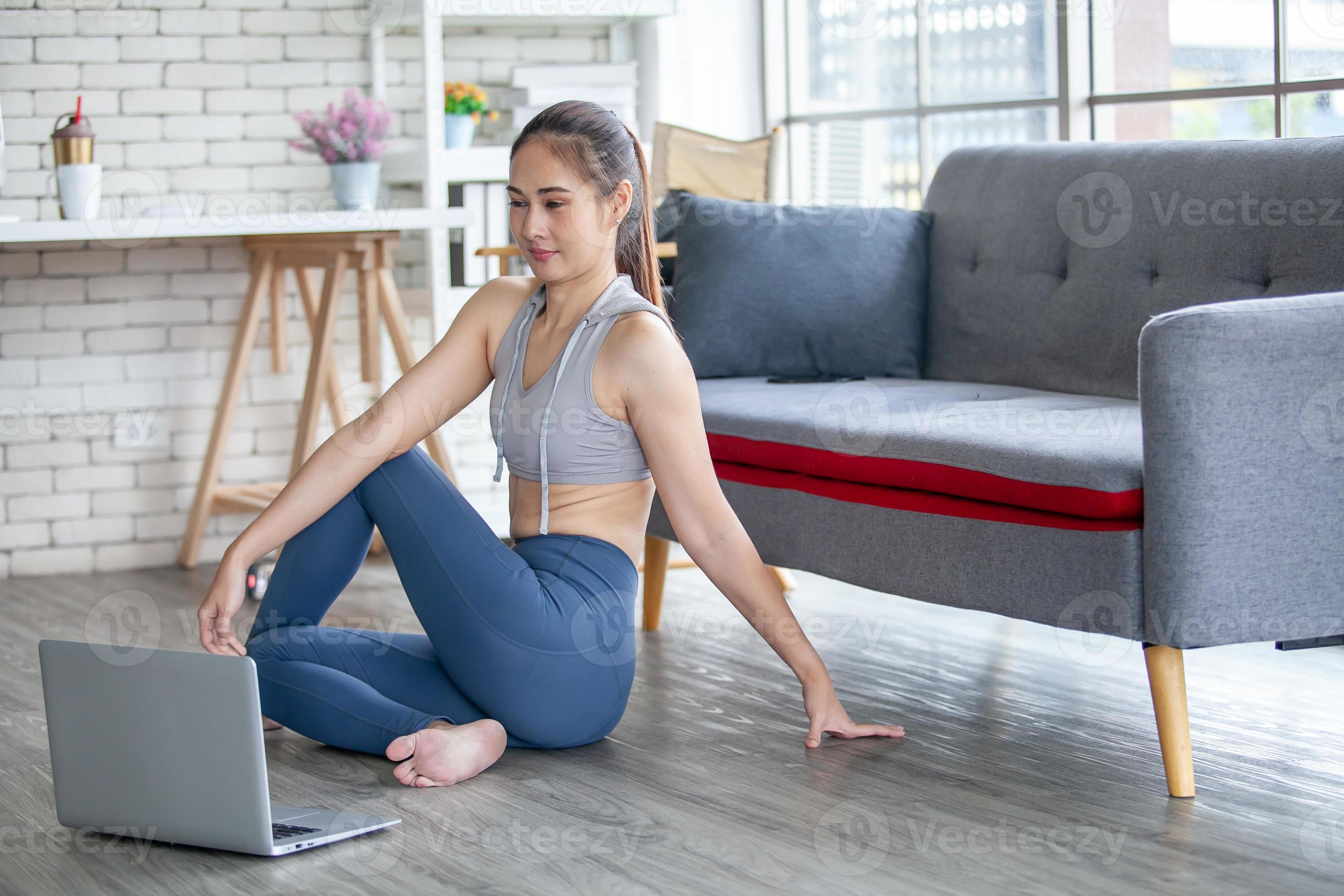 young asian woman working out and doing yoga with laptop at home ...