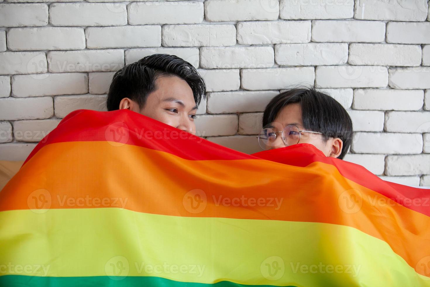 Happy asian gay couple talking together and relaxing at home on bed, LGBTQ concept. photo