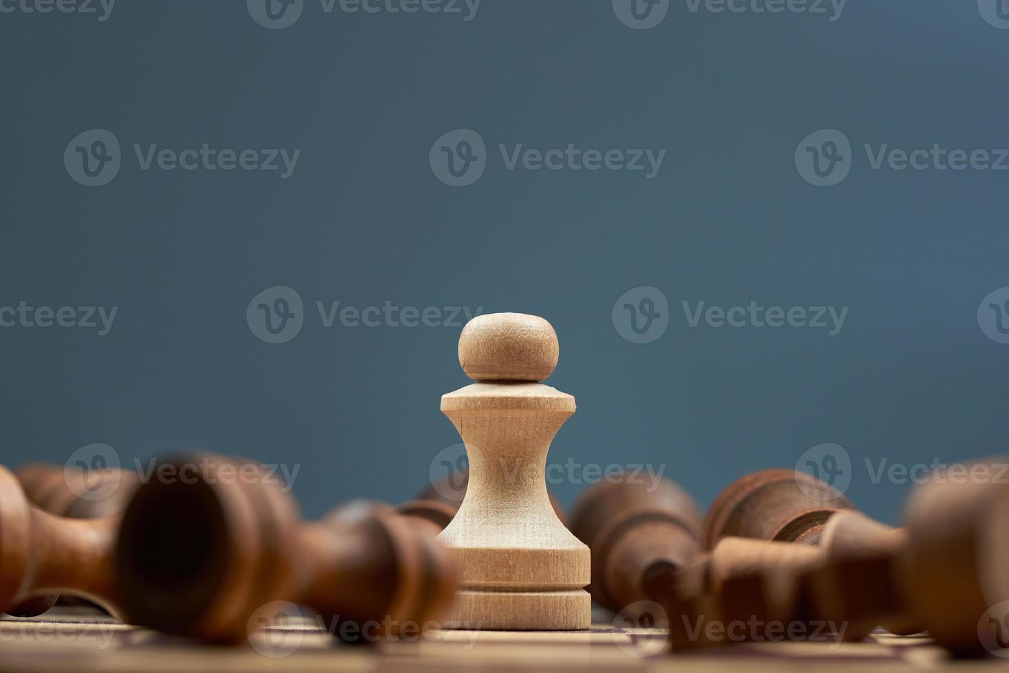 The concept of victory. The white pawn is standing, the black pieces are lying around. photo