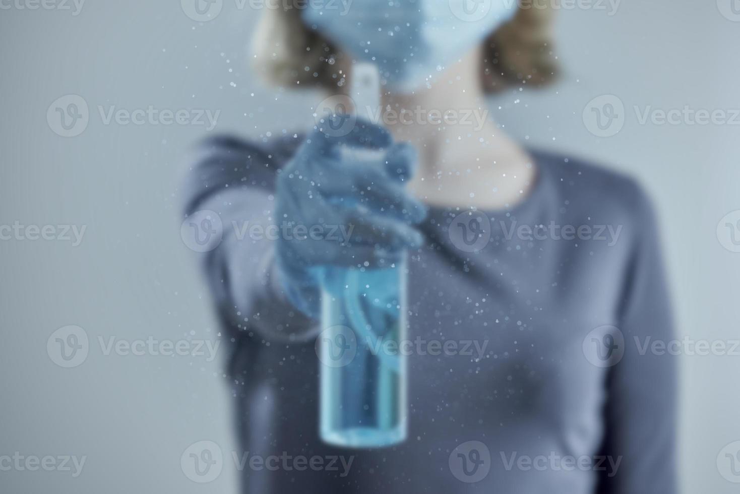 A girl in a medical mask blurs the transparent surface with a sanitizer. Photo with bokeh. Front view.