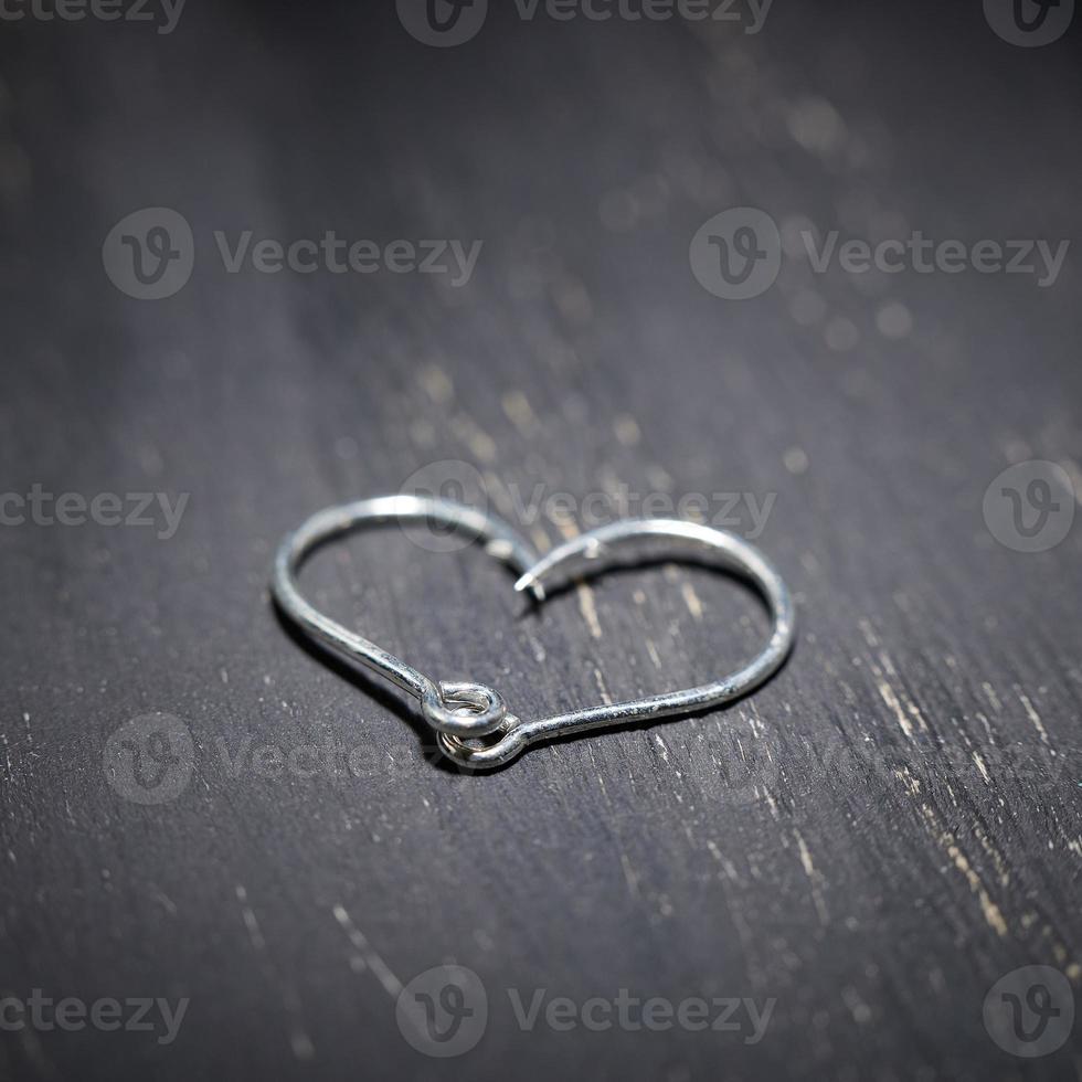 Heart-shaped fish hooks on a dark background. photo