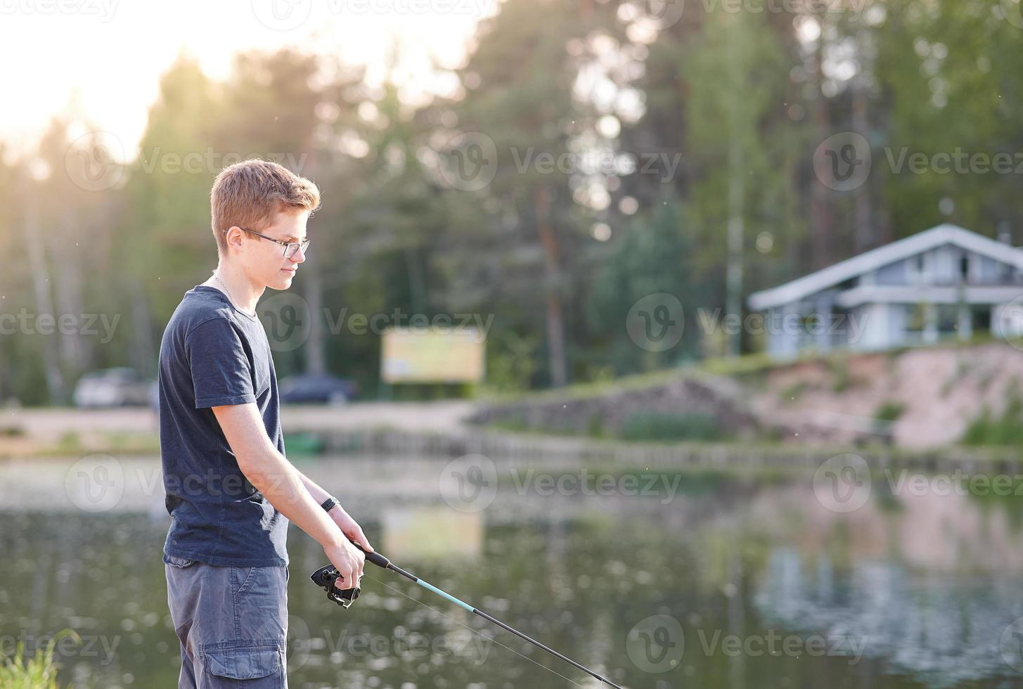 Young guy fishing on Lake with rod . Travel Lifestyle concept summer vacations. photo