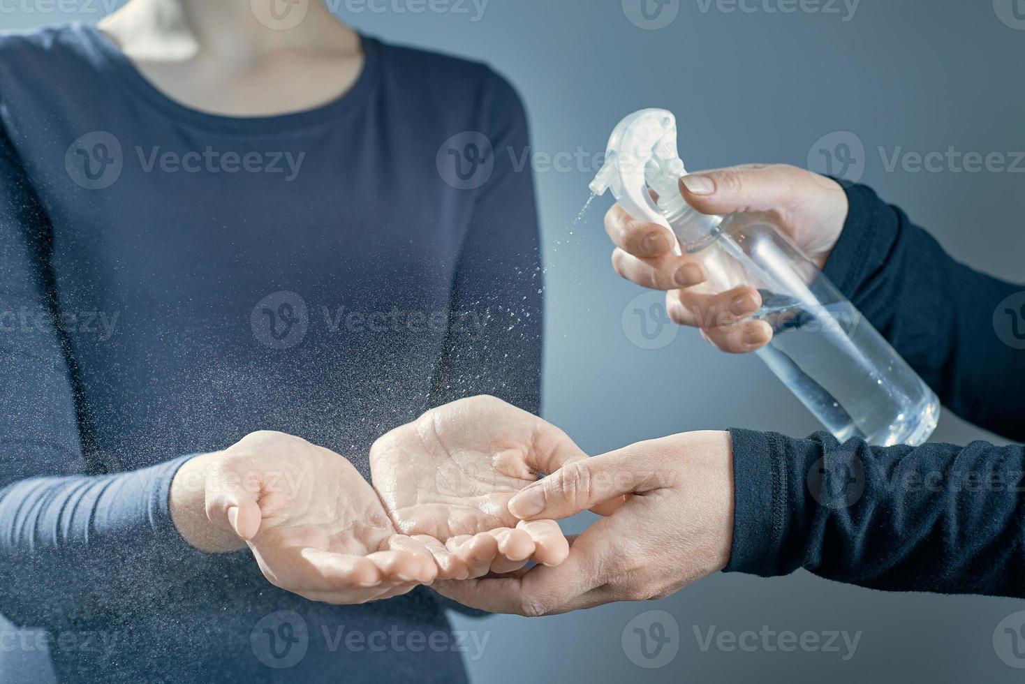 Women's hands are treated with a sanitizer girl's hands on a gray background. photo
