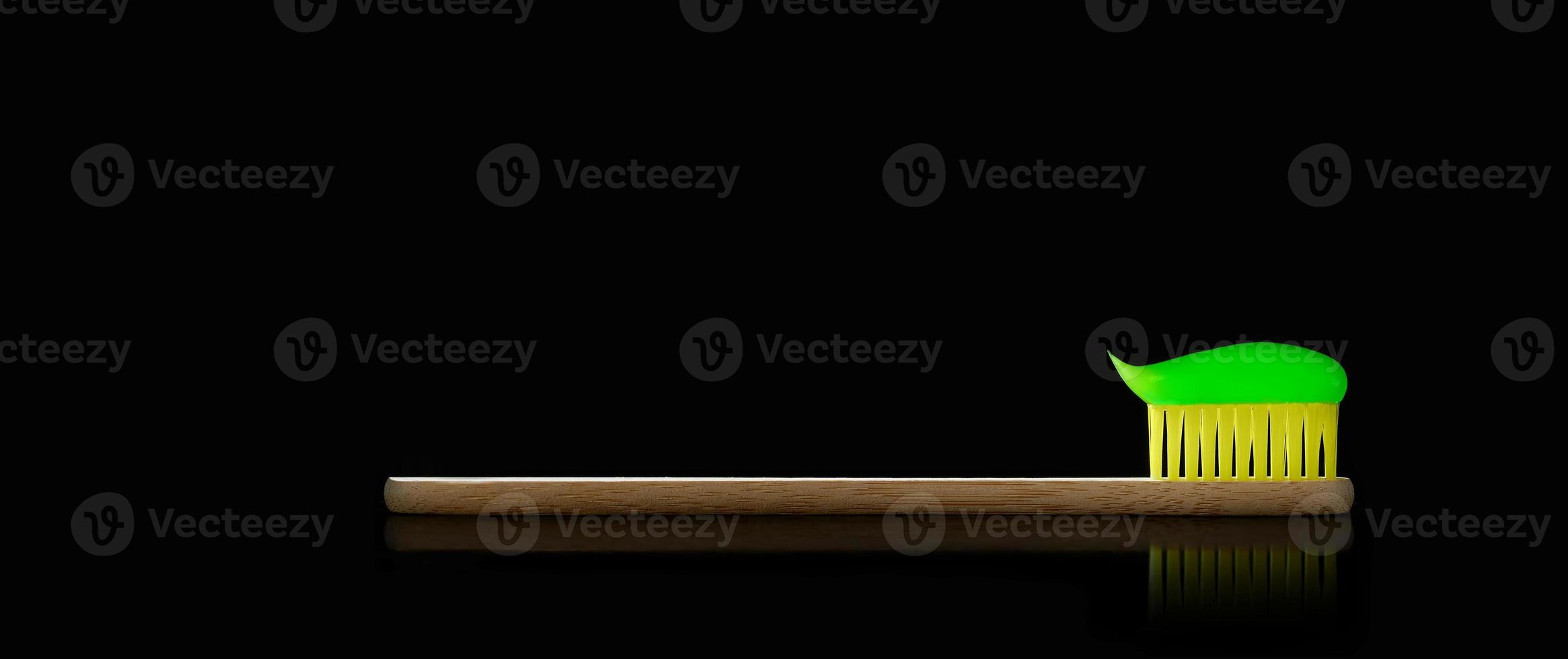 Natural bamboo toothbrush with yellow bristles on black isolated background. Oral care and dental health. Photo with copy space.
