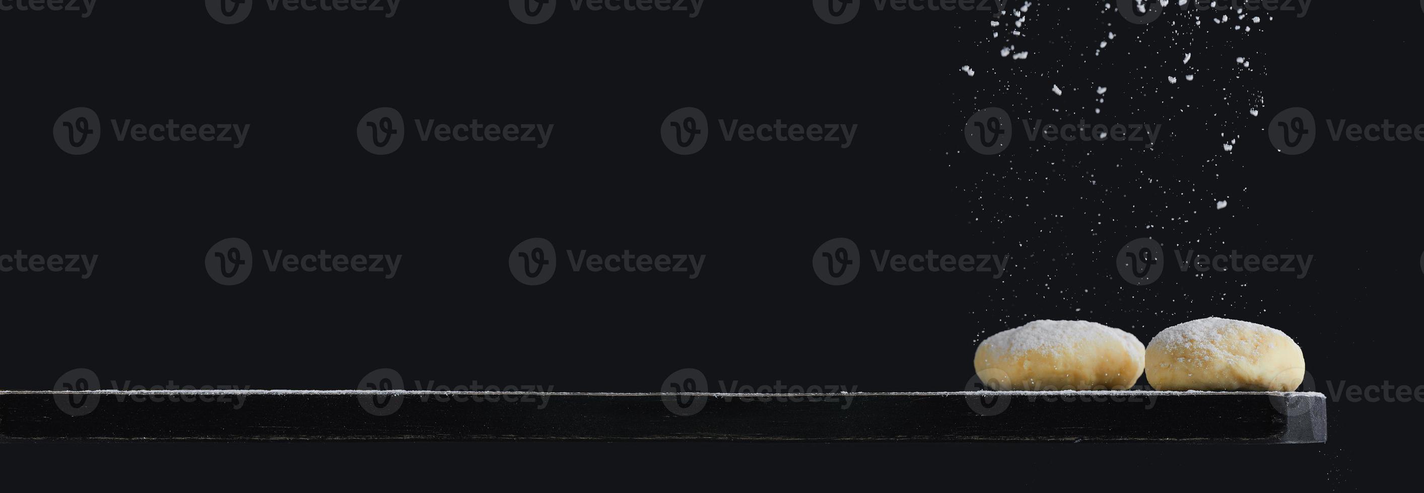 Freshly cooked yeast dough on a wooden board on a black background. Photo with copy space.