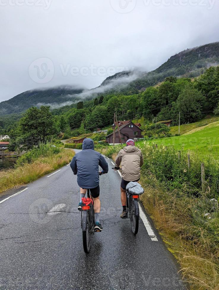 Two cycling male tourists moving on Norway fjords coastal road 8 photo