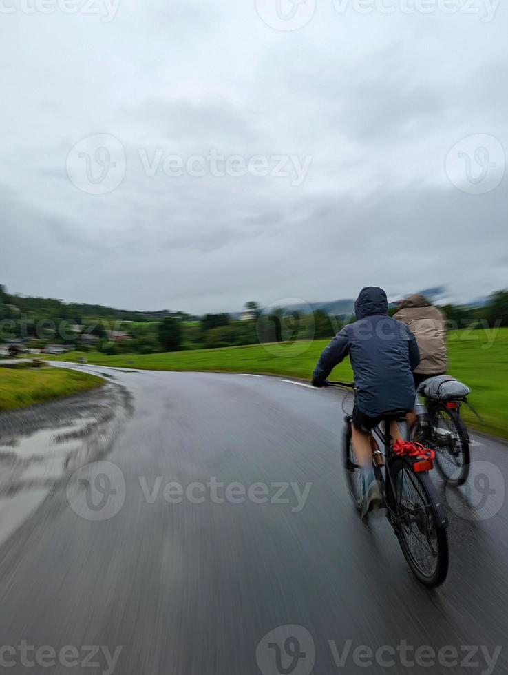 Two cycling male tourists moving rapidly on Norway fjords coastal road 6 photo