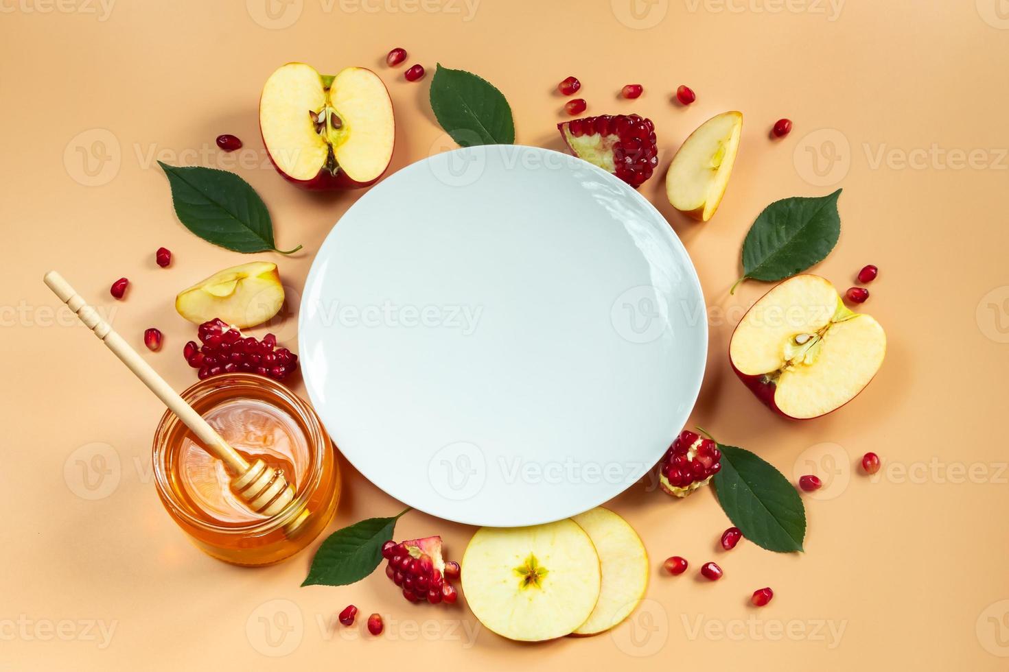 Happy Rosh Hashanah. Festive table decoration for the traditional Jewish holiday New Year. White plate and fruits with honey on yellow background. photo