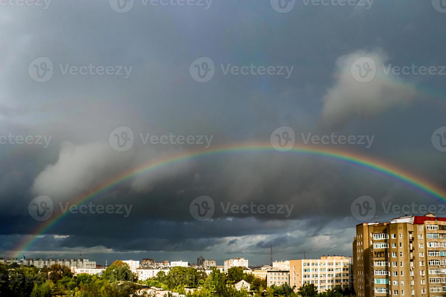 Rainbow over city. Atmospheric phenomenon in sky against background of thunderclouds. photo