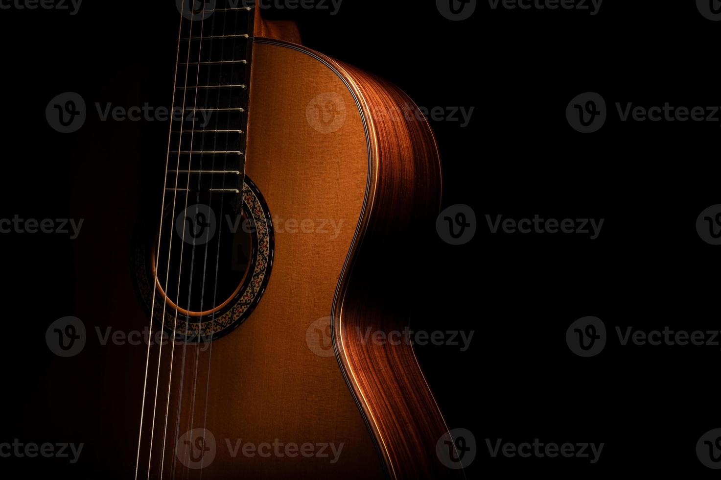 guitarra clásica de cerca, dramáticamente iluminada sobre un fondo negro con espacio de copia. foto