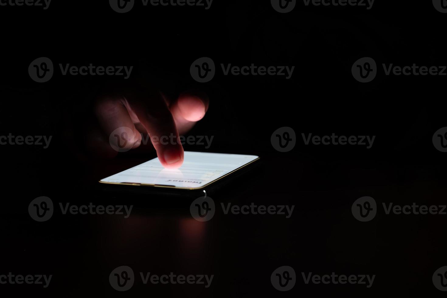 Close-up. female fingers is playing  smartphone on table. Blurred dark background. At night photo