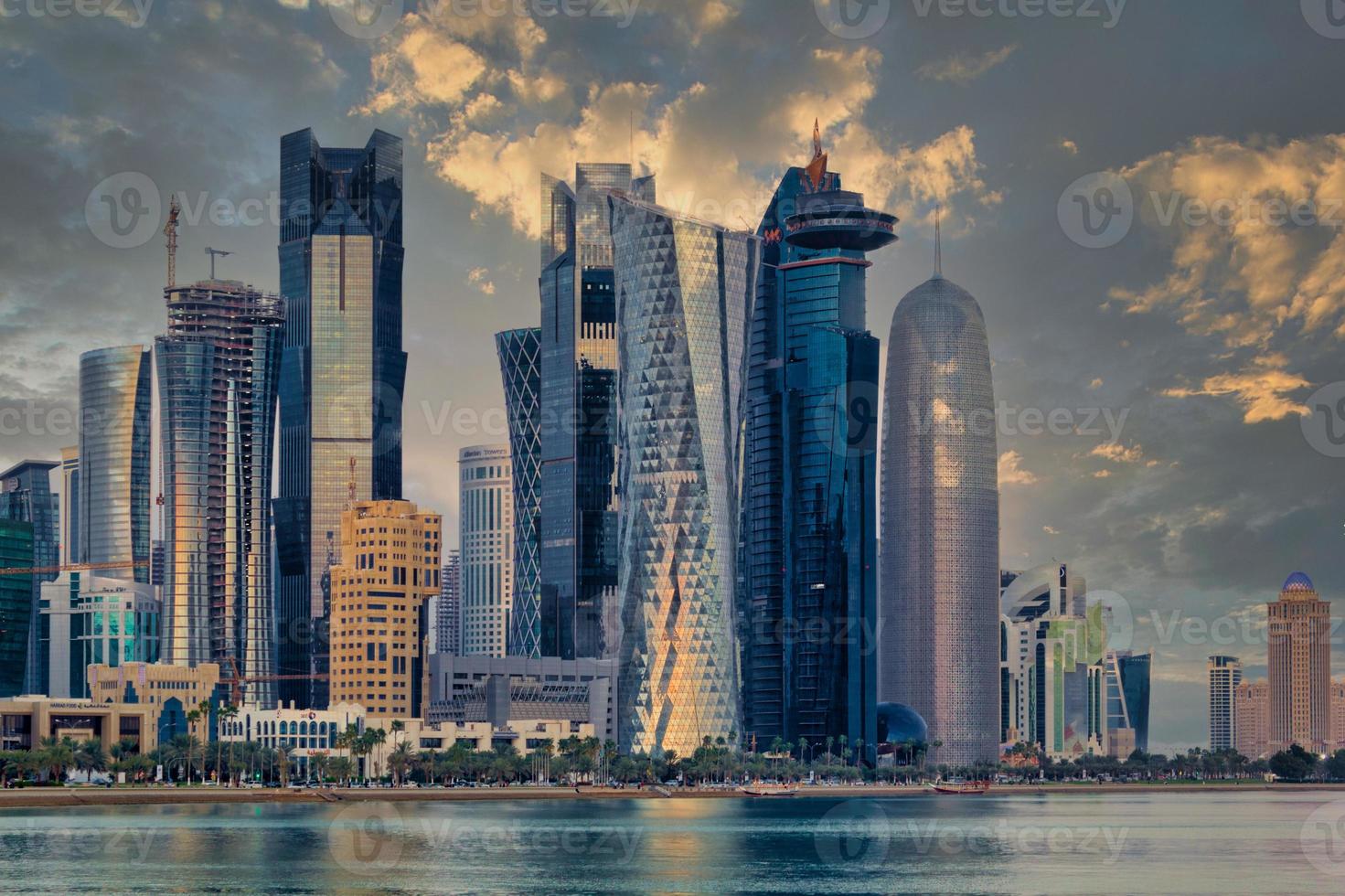 Doha Qatar skyline sunset view showing financial district in West Bay with modern skyscrapers , cars, trees and clouds in the sky. photo