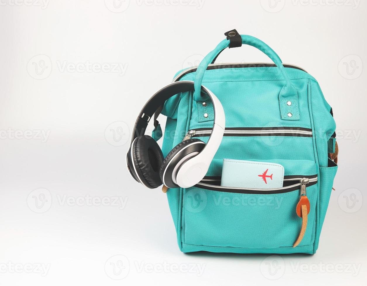 mochila verde con tapa de pasaporte y auriculares sobre fondo blanco con espacio de copia... concepto de accesorios de viaje. foto