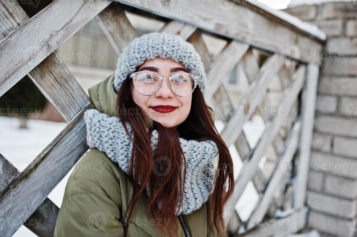 Portrait of brunette girl in gray scarf and hat, glasses at cold weather. photo