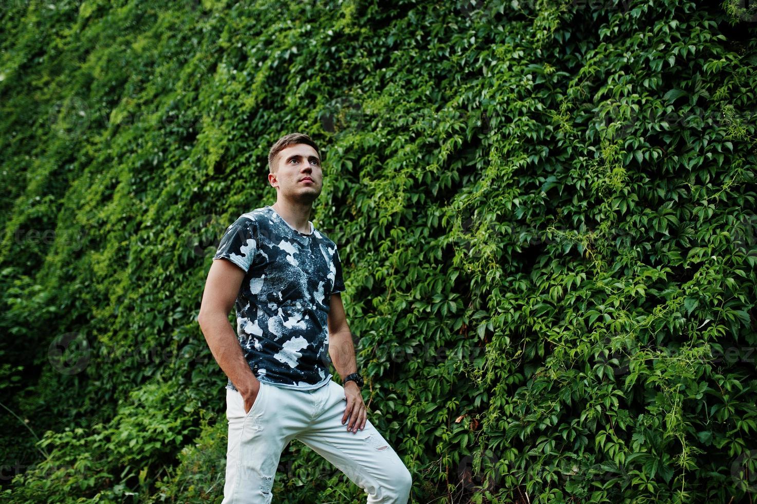 Lifestyle portrait of handsome man posing against greenery wall. photo