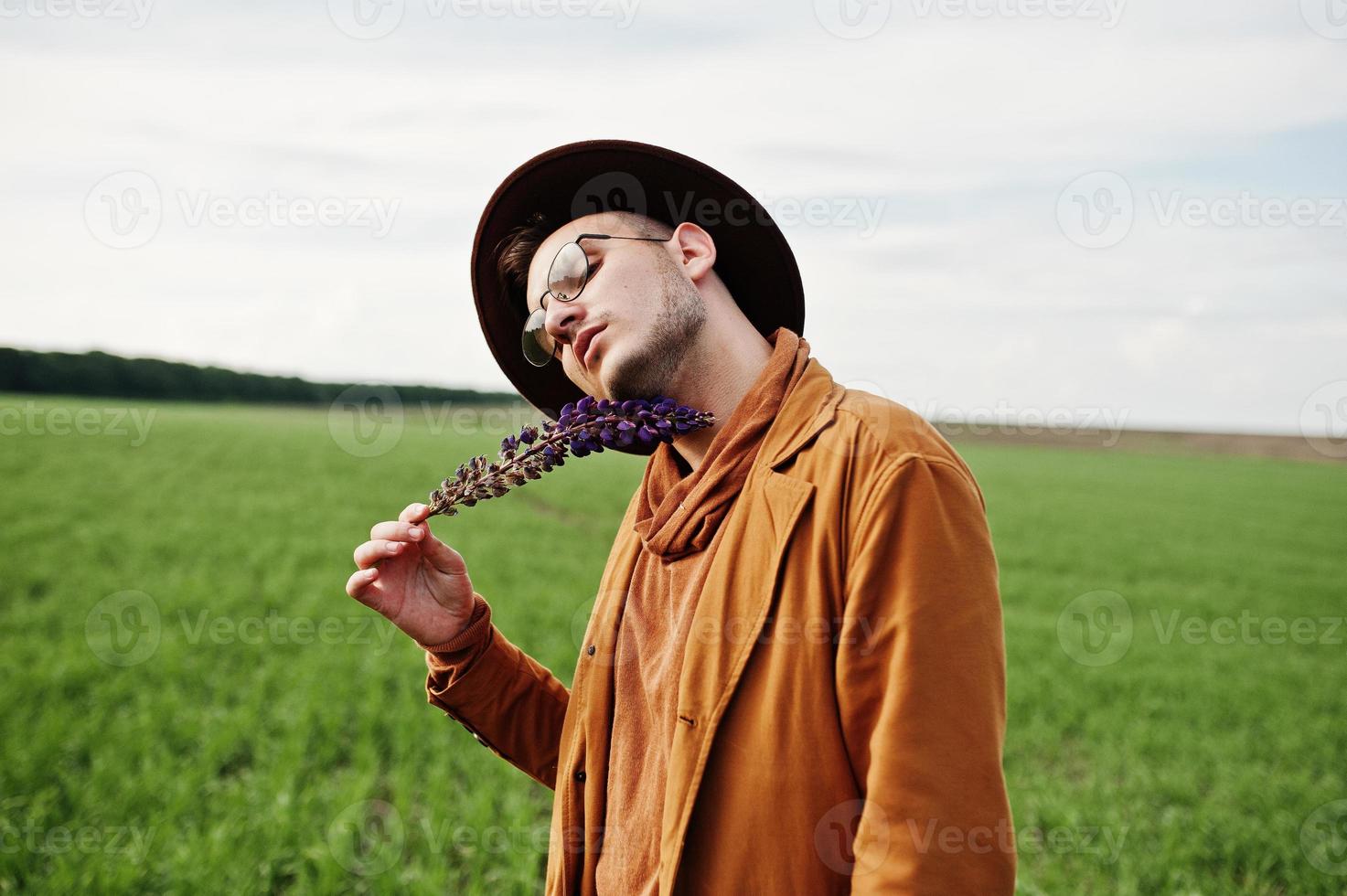 hombre elegante con gafas, chaqueta marrón y sombrero en campo verde. 10282454 Foto de Vecteezy