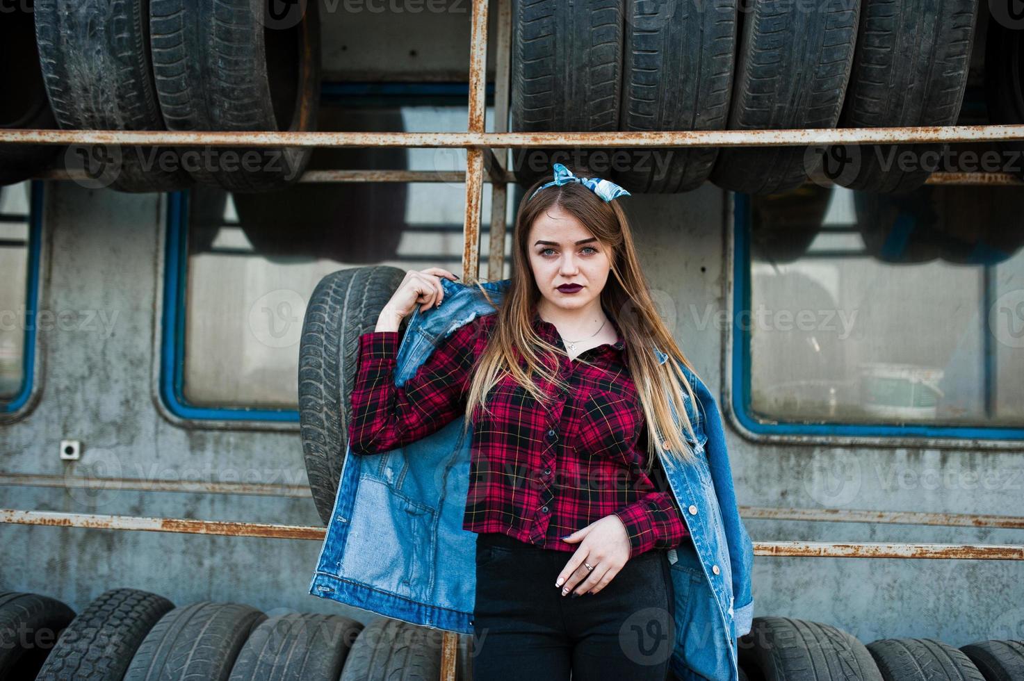 Young hipster girl in jeans jacket and head scarf at tire fitting zone. photo