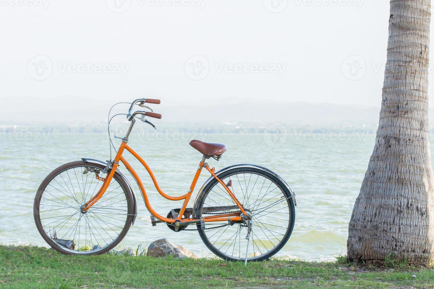 bicicleta naranja con el telón de fondo de las montañas y el mar con un cálido sol. foto