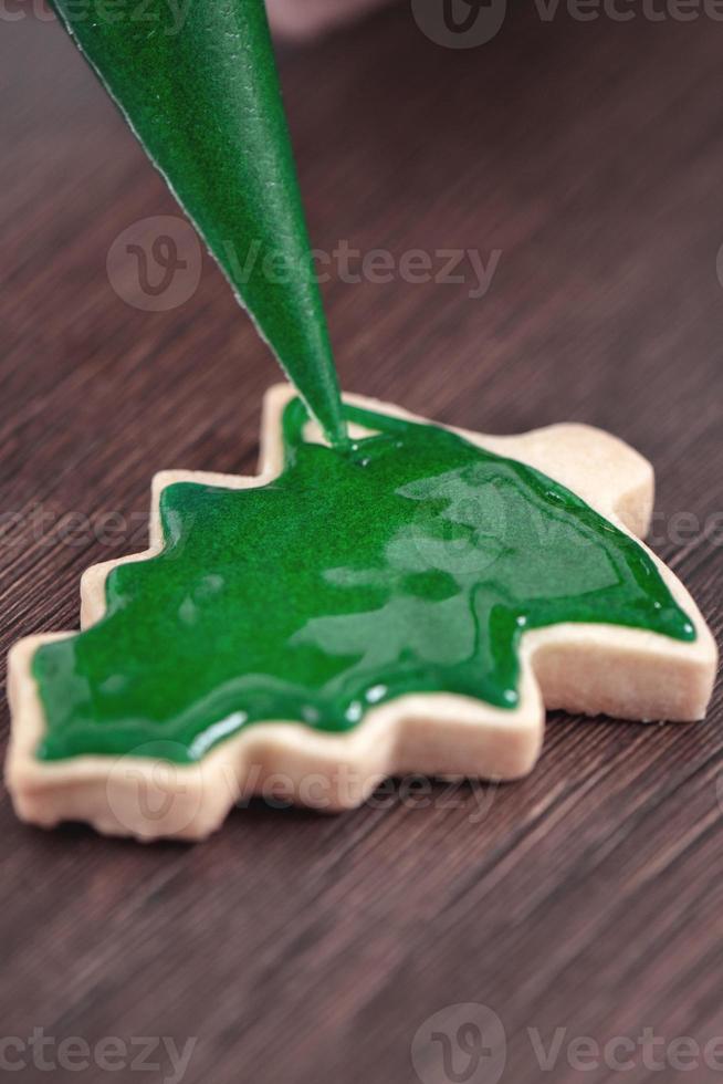 Close up of drawing Christmas tree sugar cookie on wooden table background with icing. photo