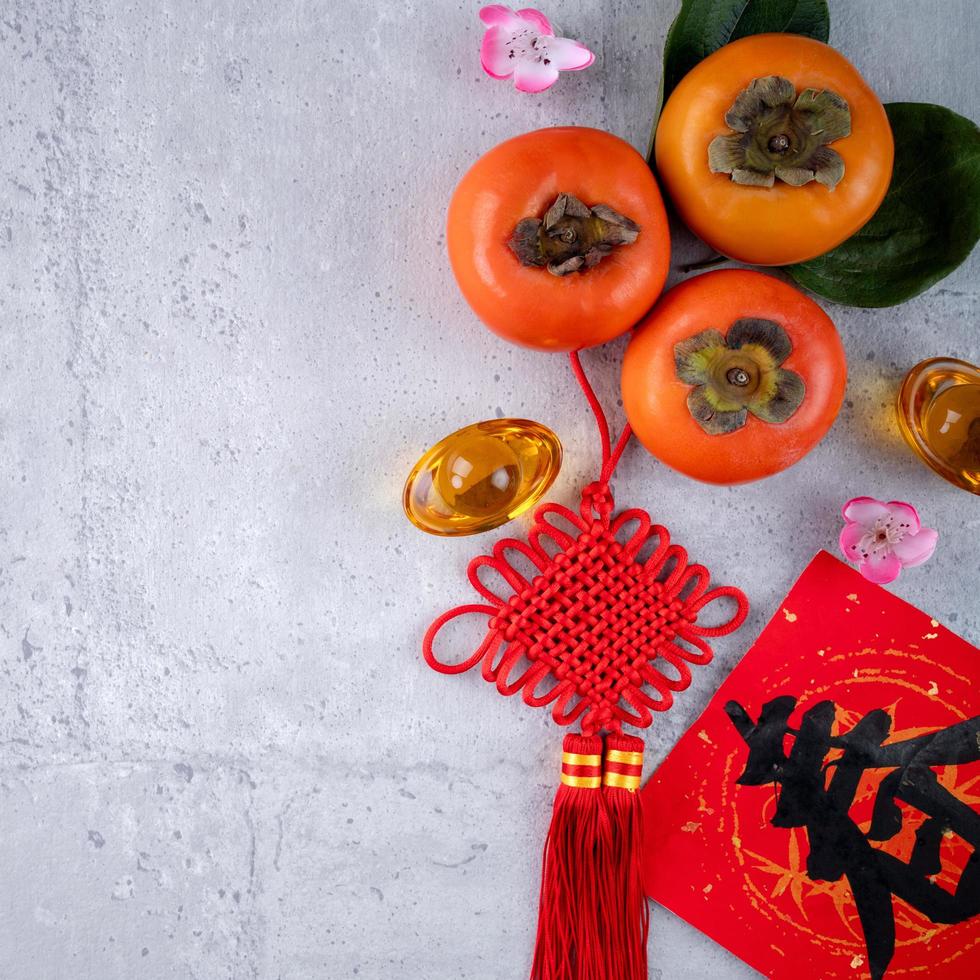 Top view of fresh sweet persimmons with leaves on gray table background for Chinese lunar new year photo