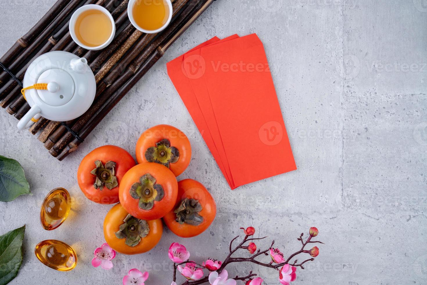 Top view of fresh sweet persimmons with leaves on gray table background for Chinese lunar new year photo