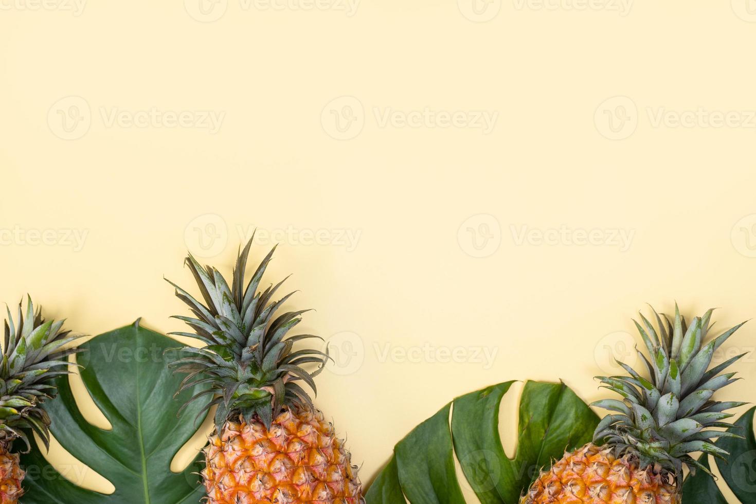 Beautiful pineapple on tropical palm monstera leaves isolated on bright pastel yellow background, top view, flat lay, overhead above summer fruit. photo