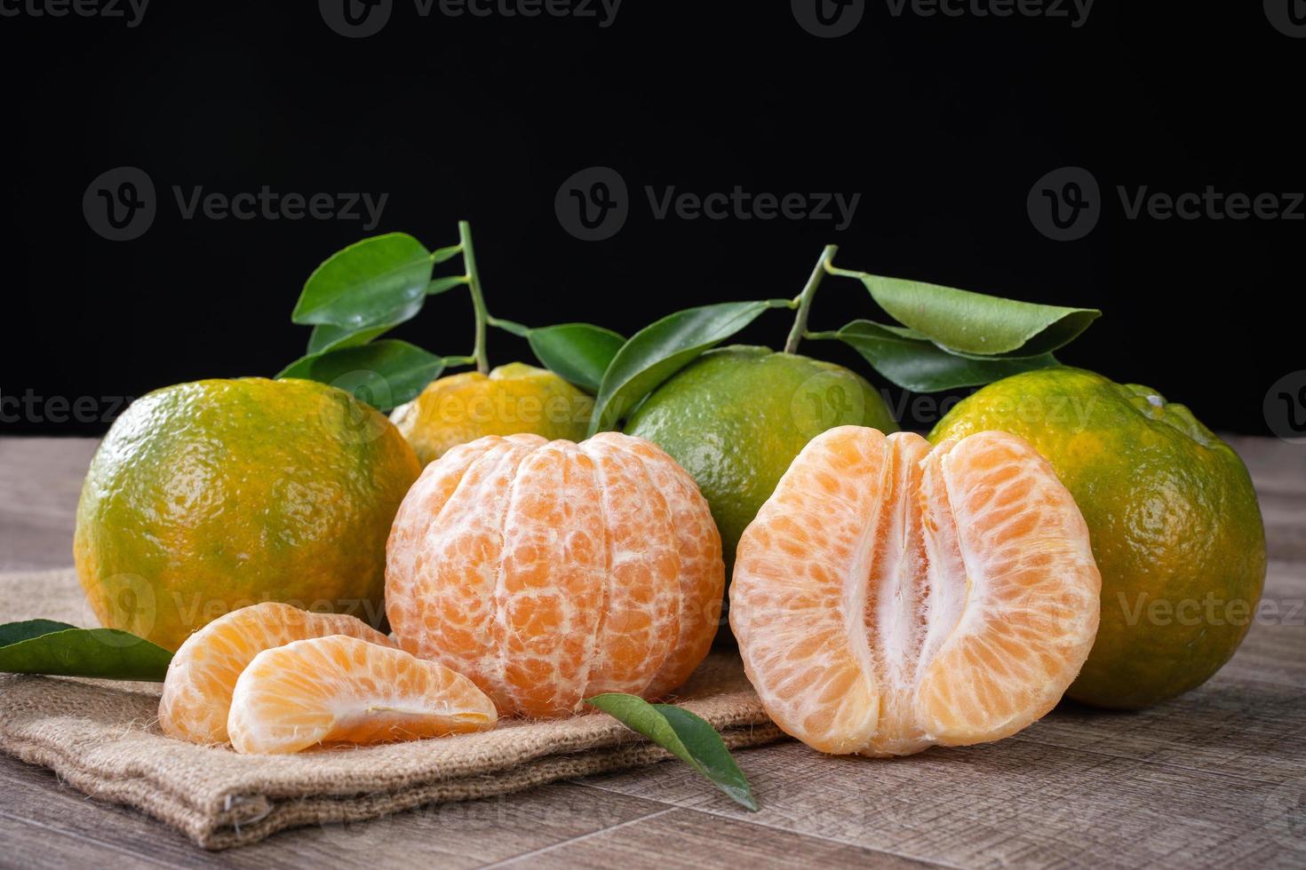 Fresh green tangerine mandarin orange on dark wooden table background. photo